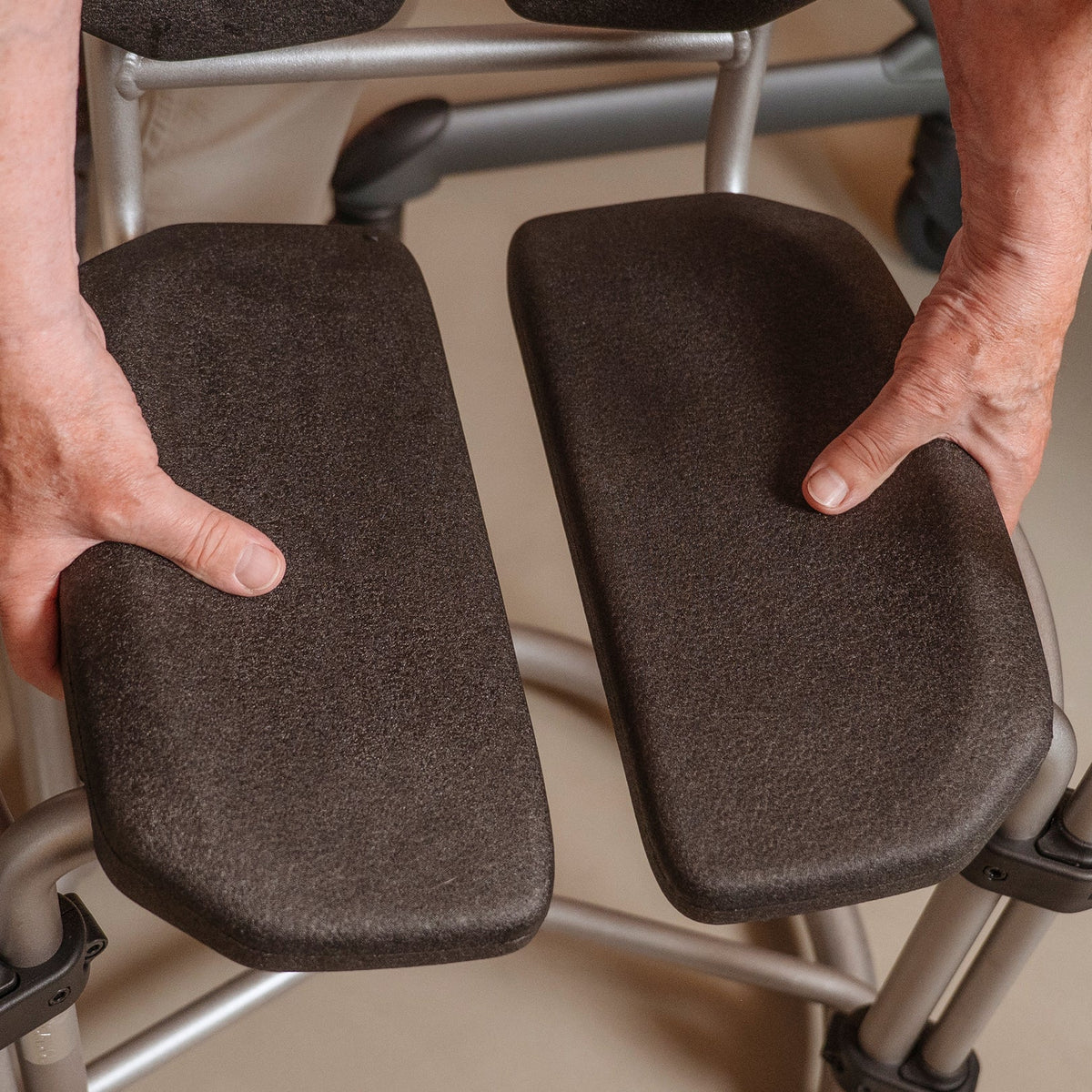 Hands adjusting the two halves of the Saljol shower chair seat to set the hygiene cutout
