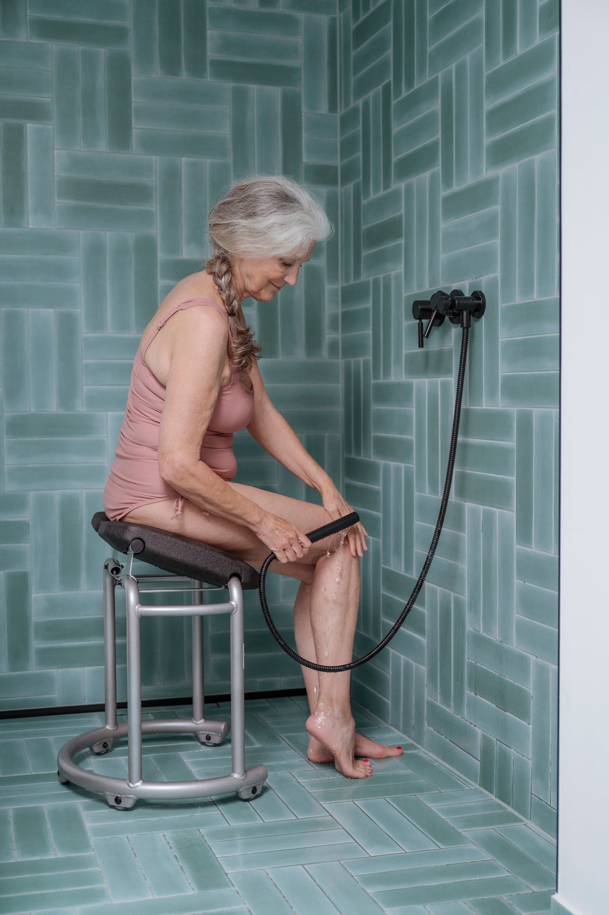 A woman seated on the Saljol shower stool washing her lower leg